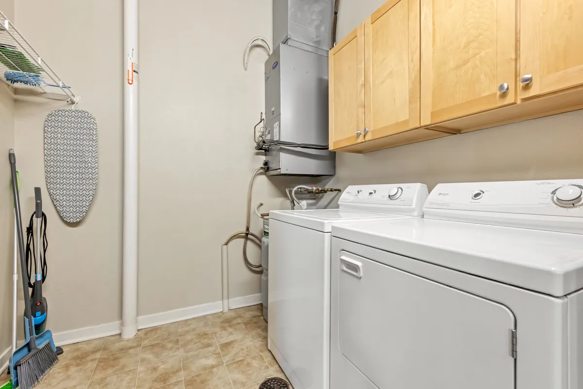 A well-organized laundry area with modern appliances, wooden cabinetry, and an ironing board, providing a practical space for business travelers to quickly freshen up their attire.