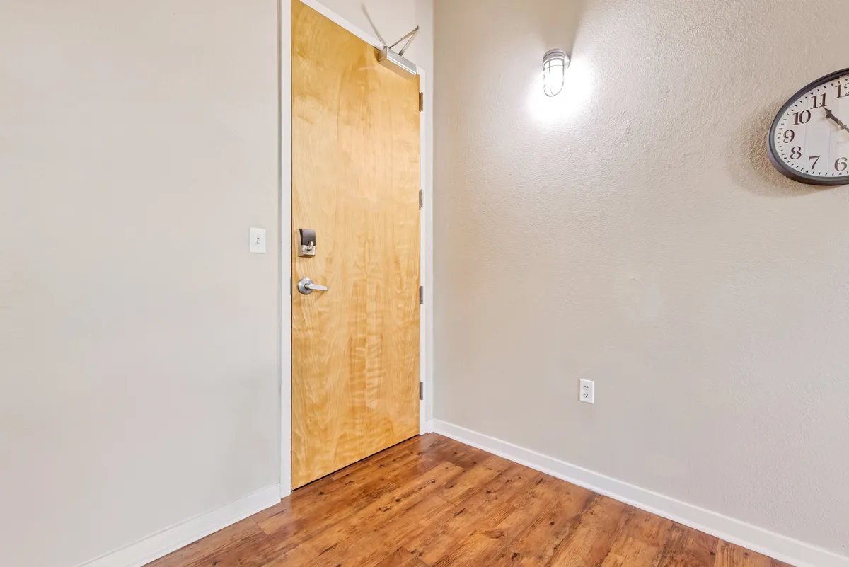 An inviting entryway with a solid wooden door, classic wall clock, and elegant lighting, creating a memorable first impression and setting the tone for the home's character-rich interior.